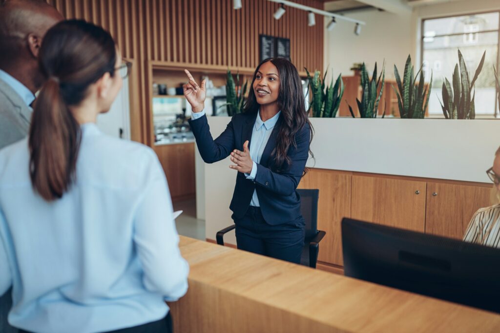 Smiling African American concierge giving two hotel guests room directions